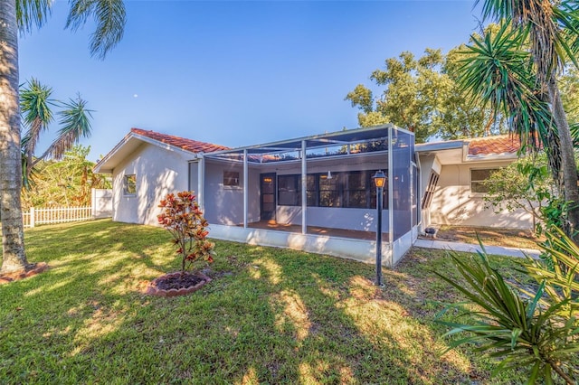 rear view of house featuring a sunroom, a lanai, and a lawn