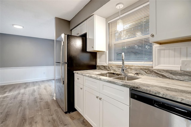 kitchen featuring sink, hanging light fixtures, light hardwood / wood-style flooring, white cabinetry, and stainless steel appliances