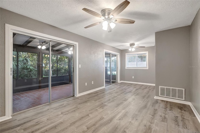 unfurnished room featuring ceiling fan, beamed ceiling, light hardwood / wood-style floors, and a textured ceiling