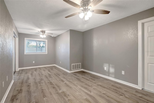 empty room featuring ceiling fan, a textured ceiling, and light hardwood / wood-style flooring