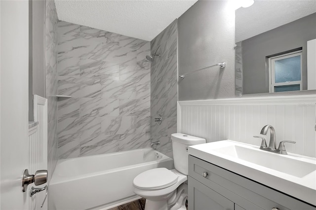 full bathroom with toilet, vanity, a textured ceiling, and tiled shower / bath