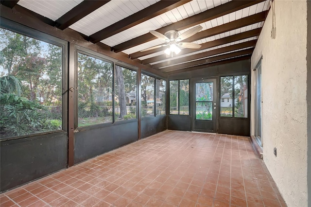 unfurnished sunroom featuring vaulted ceiling with beams, ceiling fan, and a wealth of natural light