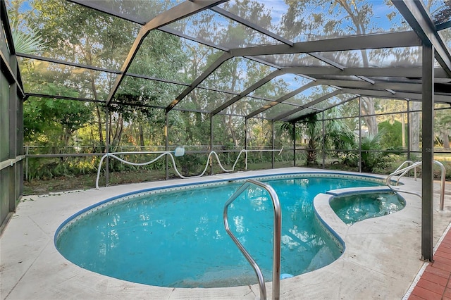 view of swimming pool with glass enclosure, a patio area, and an in ground hot tub