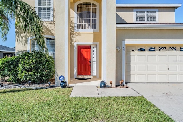 property entrance featuring a garage and a lawn