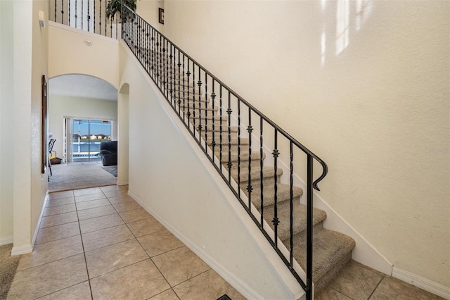 stairs with a towering ceiling and tile patterned floors