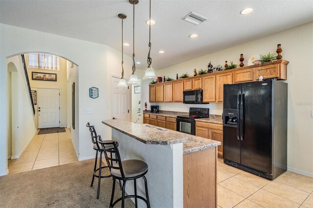 kitchen with a breakfast bar area, a textured ceiling, black appliances, pendant lighting, and a center island