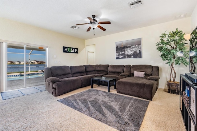 carpeted living room with a water view and ceiling fan