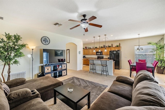 living room featuring a textured ceiling, light tile patterned floors, and ceiling fan