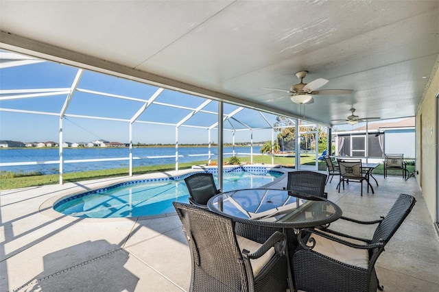 view of pool with a patio, a water view, glass enclosure, and ceiling fan