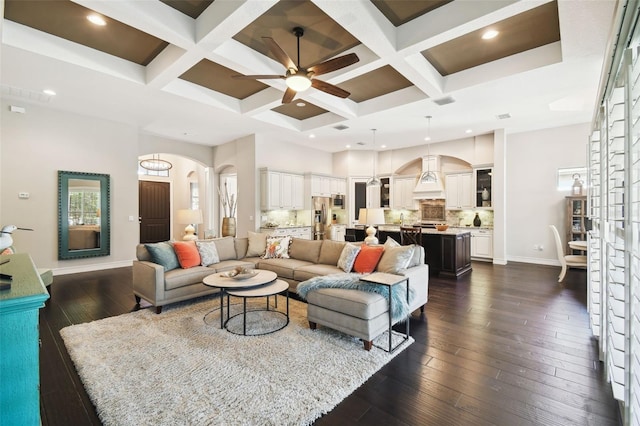 living room with beam ceiling, ceiling fan, dark wood-type flooring, and coffered ceiling