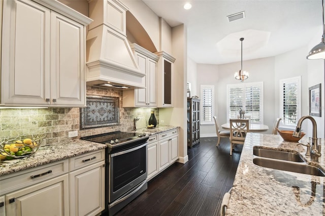 kitchen with stainless steel electric range, sink, hanging light fixtures, and custom exhaust hood