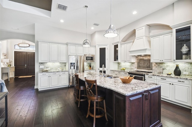 kitchen featuring sink, decorative backsplash, an island with sink, dark hardwood / wood-style flooring, and stainless steel appliances