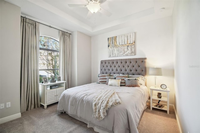 bedroom with carpet floors, a tray ceiling, and ceiling fan