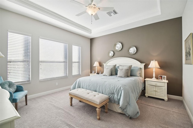 carpeted bedroom featuring a tray ceiling and ceiling fan