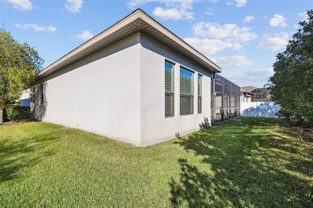 view of side of home featuring a lawn and glass enclosure