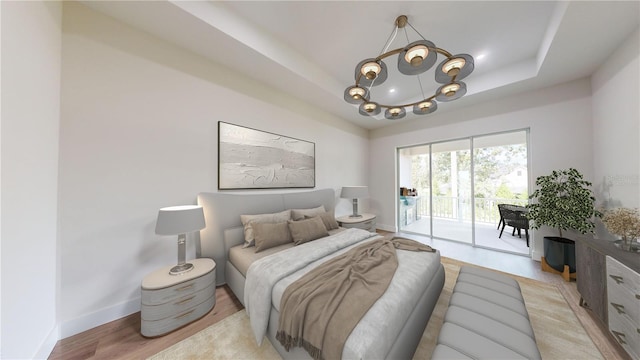 bedroom with a tray ceiling, a notable chandelier, access to outside, and light hardwood / wood-style flooring