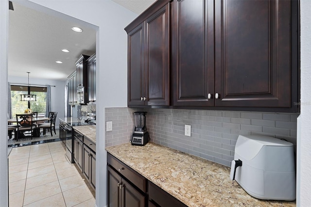 kitchen featuring hanging light fixtures, electric range, dark brown cabinetry, light tile patterned floors, and tasteful backsplash