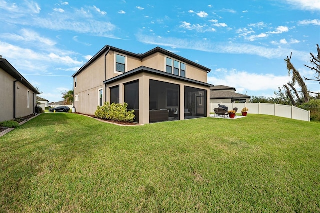 rear view of property featuring a yard, a sunroom, and a patio area