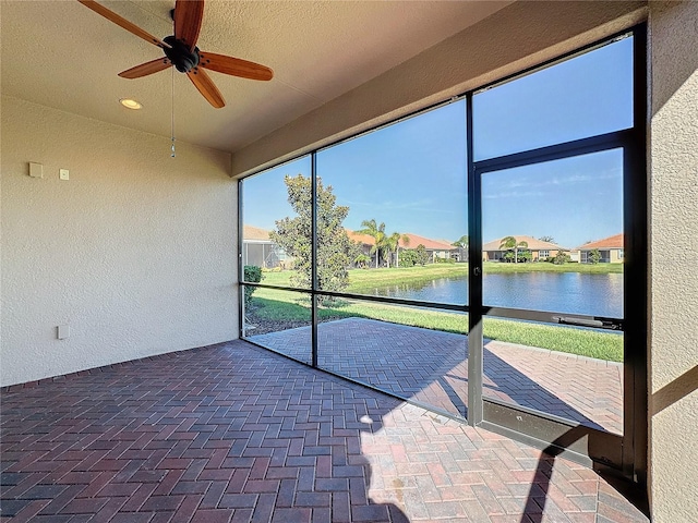 unfurnished sunroom with a water view and ceiling fan