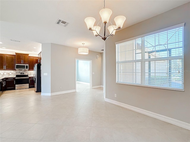 spare room with a notable chandelier and light tile patterned flooring