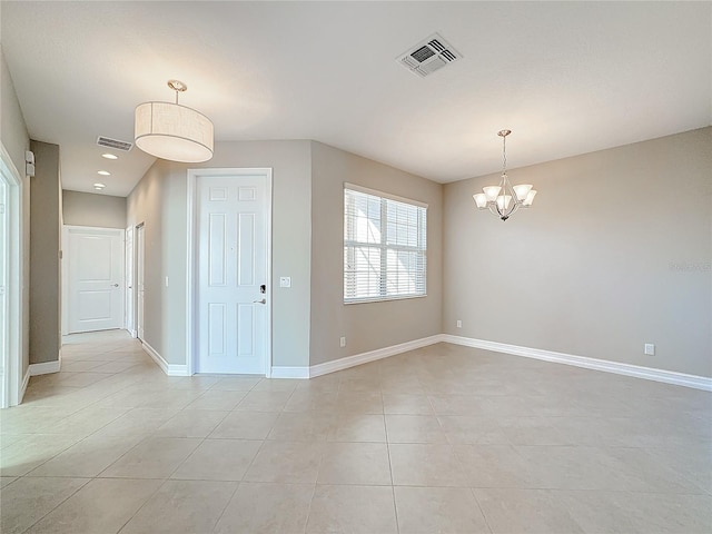 spare room featuring a chandelier and light tile patterned flooring