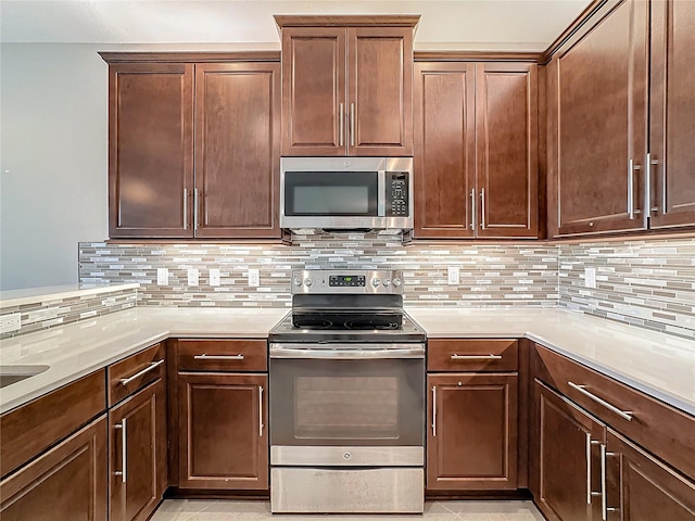 kitchen with backsplash, light tile patterned floors, and stainless steel appliances