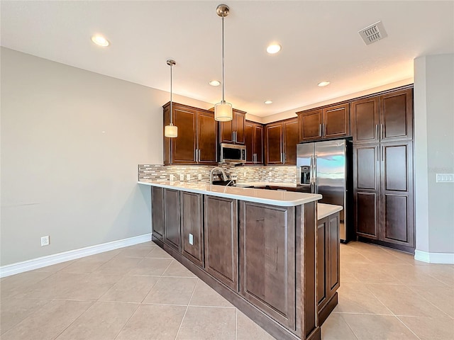 kitchen featuring tasteful backsplash, kitchen peninsula, decorative light fixtures, light tile patterned floors, and appliances with stainless steel finishes