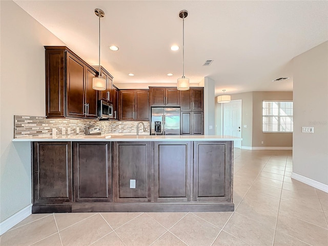 kitchen featuring hanging light fixtures, tasteful backsplash, dark brown cabinets, kitchen peninsula, and stainless steel appliances