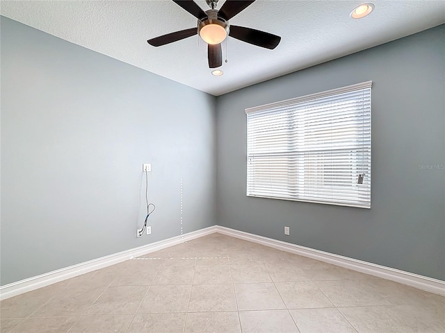 empty room featuring ceiling fan, light tile patterned floors, and a textured ceiling