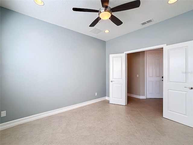 unfurnished bedroom featuring ceiling fan, light tile patterned floors, and a textured ceiling