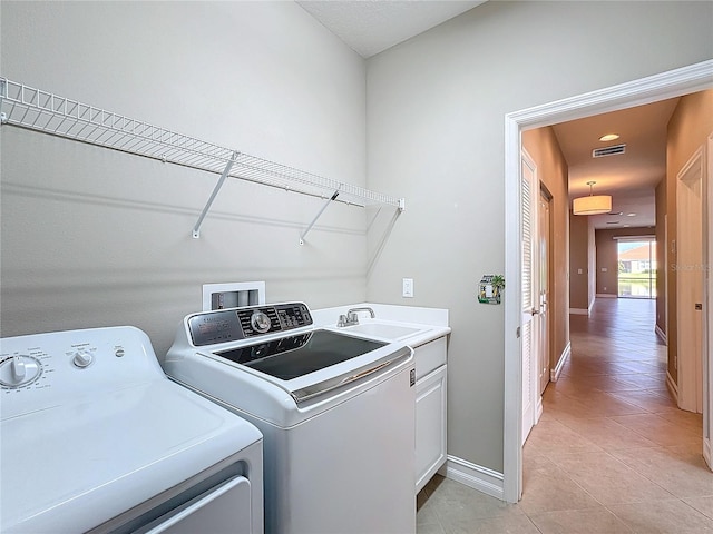 washroom featuring separate washer and dryer, sink, light tile patterned floors, and cabinets