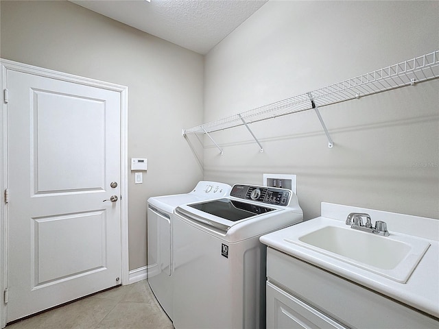 laundry room featuring sink, light tile patterned floors, a textured ceiling, and independent washer and dryer