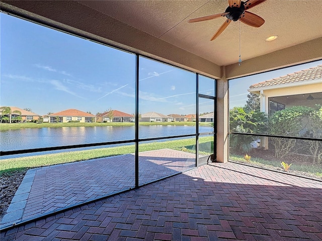 unfurnished sunroom with a water view and ceiling fan