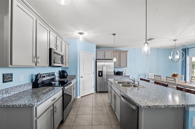 kitchen featuring sink, appliances with stainless steel finishes, a kitchen island with sink, gray cabinetry, and pendant lighting