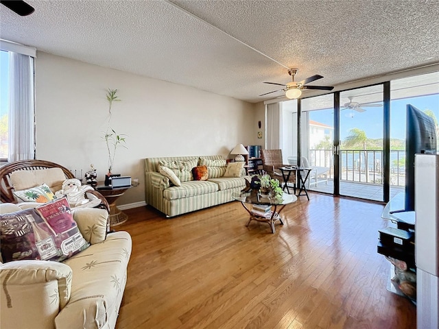 living room featuring expansive windows, ceiling fan, hardwood / wood-style flooring, and a textured ceiling