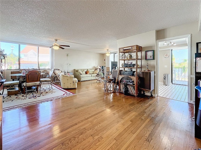 living room with hardwood / wood-style floors, a textured ceiling, a healthy amount of sunlight, and ceiling fan