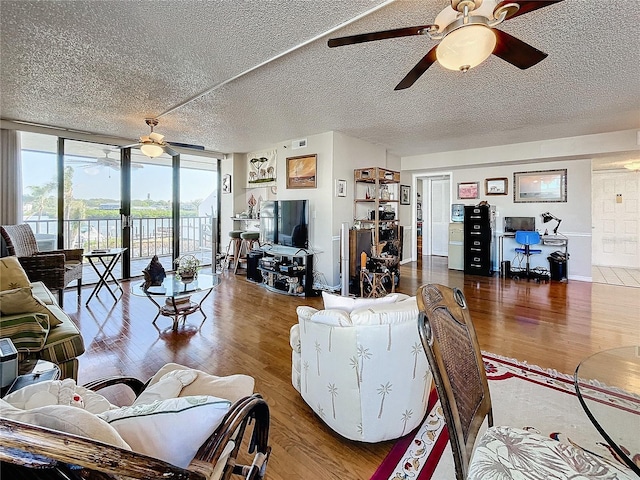 living room featuring hardwood / wood-style flooring, floor to ceiling windows, ceiling fan, and a textured ceiling