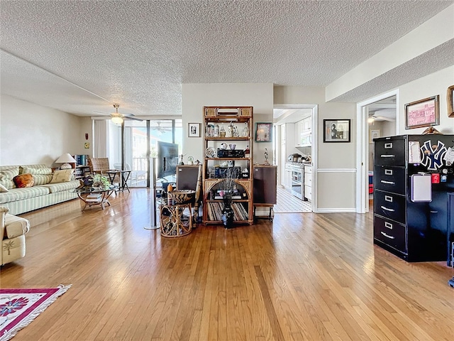 living room featuring a textured ceiling, wood-type flooring, floor to ceiling windows, and ceiling fan