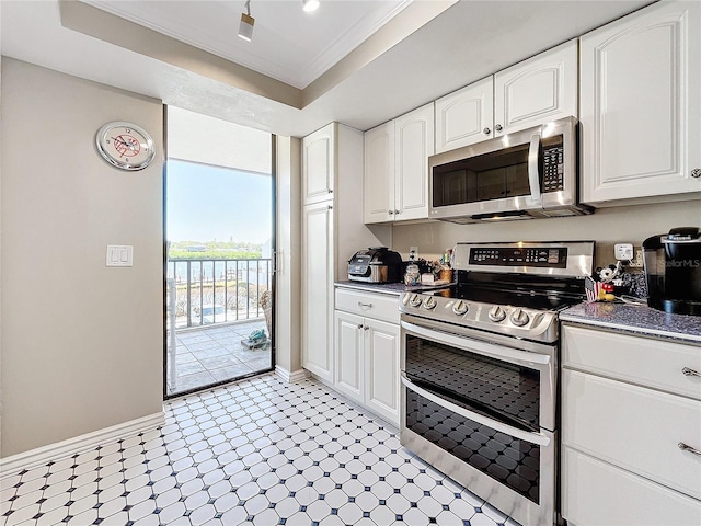 kitchen with crown molding, a tray ceiling, white cabinets, and appliances with stainless steel finishes