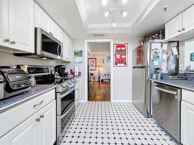 kitchen featuring crown molding, stainless steel appliances, a tray ceiling, and white cabinets