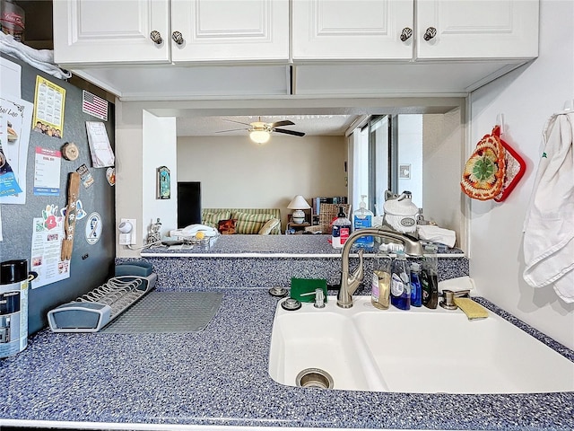 interior space featuring ceiling fan, sink, and white cabinets