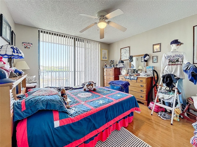 bedroom featuring ceiling fan, hardwood / wood-style floors, and a textured ceiling