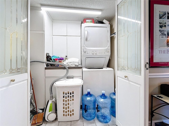 washroom with stacked washer / drying machine, a textured ceiling, and light tile patterned floors