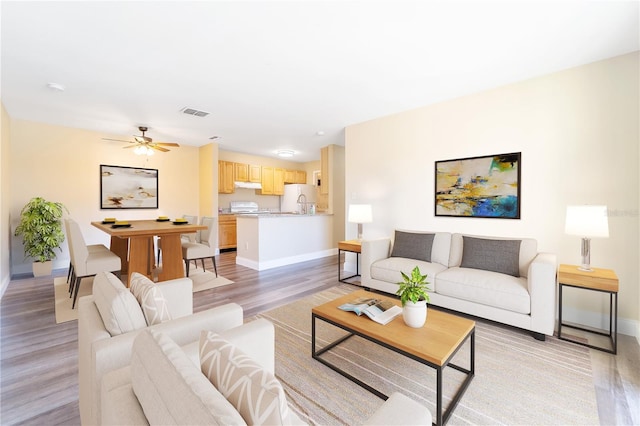 living room featuring light hardwood / wood-style floors and ceiling fan