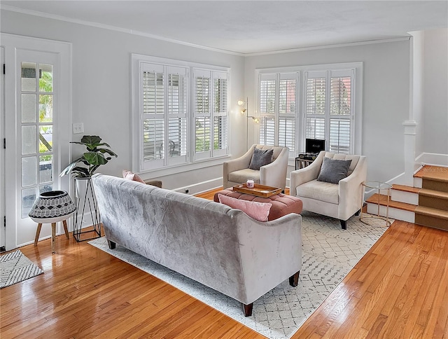 living area with stairs, ornamental molding, and light wood-style floors