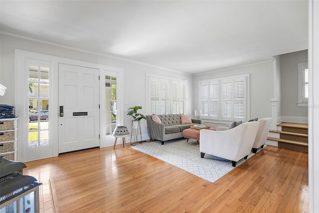 living room featuring ornamental molding, a wealth of natural light, stairway, and light wood-style flooring