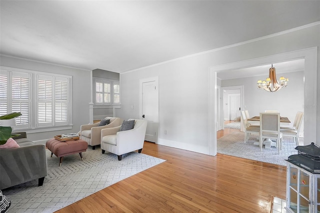 living area featuring an inviting chandelier, crown molding, baseboards, and wood finished floors