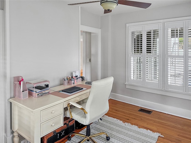 office with baseboards, visible vents, a ceiling fan, and wood finished floors