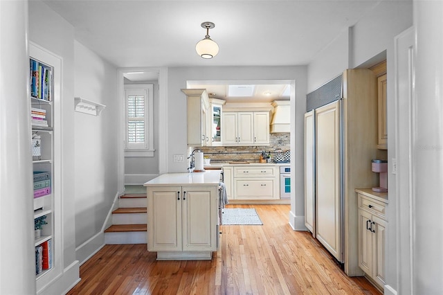 kitchen with light wood-style floors, tasteful backsplash, light countertops, and oven