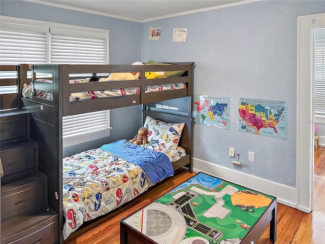 bedroom featuring ornamental molding, wood finished floors, and baseboards